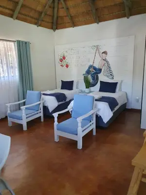 a room with four beds and blue chairs at Pomegranate Selfcatering apartment in Nelspruit