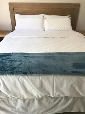 a bed with a blue and white blanket on it at Pafuri Gate Guesthouse in Mabalingwe Game Reserve