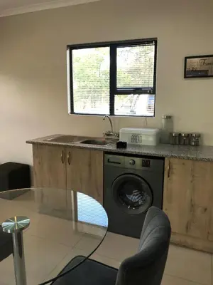 a kitchen with a washing machine and a window at Pafuri Gate Guesthouse in Mabalingwe Game Reserve