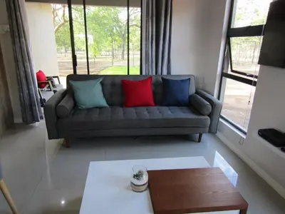 a living room with a couch with three pillows on it at Pafuri Gate Guesthouse in Mabalingwe Game Reserve