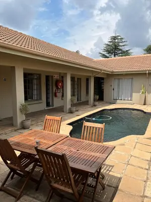 a wooden table and chairs next to a swimming pool at Euforia Guesthouse in Middelburg