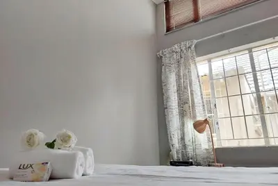 a bedroom with a bed and a window with roses at Cozy Hatfield Condo in Pretoria