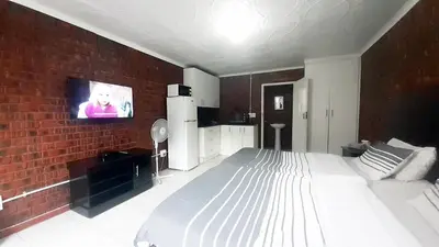a bedroom with a bed and a tv on a brick wall at Cozy Hatfield Condo in Pretoria