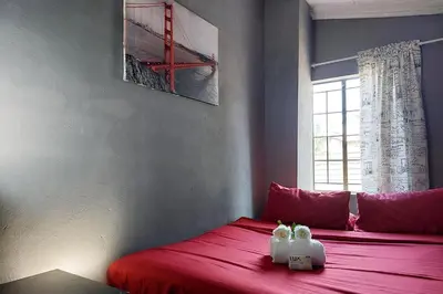 a bedroom with two stuffed animals sitting on a red bed at Cozy Hatfield Condo in Pretoria