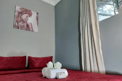 a bedroom with a bed with red sheets and a window at Cozy Hatfield Condo in Pretoria
