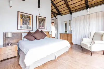 a bedroom with a white bed and a chair at Waterberg House at Zebula 8 adults and 4 kids in Mabula