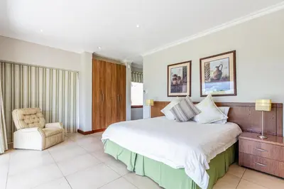 a bedroom with a large bed and a chair at Waterberg House at Zebula 8 adults and 4 kids in Mabula