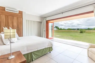 a bedroom with a bed and a large window at Waterberg House at Zebula 8 adults and 4 kids in Mabula