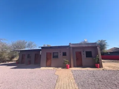 a small house with brown doors and two potted plants at Bush Inn Lodge Lephalale in Lephalale