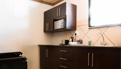 a kitchen with black cabinets and a microwave at Bush Inn Lodge Lephalale in Lephalale