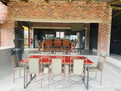 a red dining table with chairs and a brick wall at Newburg Lodge & Luxury Bush Tents, Elements Private Golf Reserve in Moheme