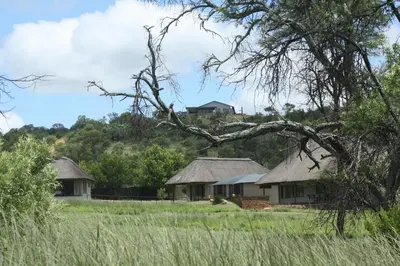 a group of houses with thatched roofs in a field at Newburg Lodge & Luxury Bush Tents, Elements Private Golf Reserve in Moheme