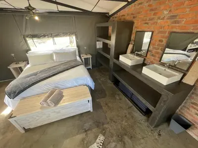 a bedroom with a bed and a sink and a mirror at Newburg Lodge & Luxury Bush Tents, Elements Private Golf Reserve in Moheme
