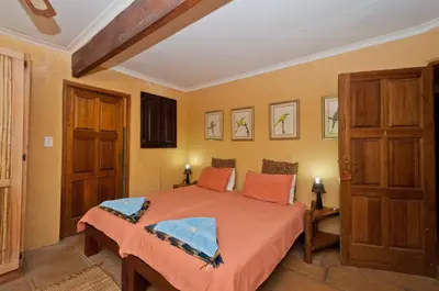 a bedroom with a large bed with orange sheets at Greenfire Hazyview Lodge in Hazyview