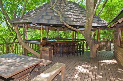 a wooden deck with a gazebo with a table and benches at Greenfire Hazyview Lodge in Hazyview
