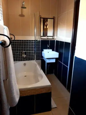 a bathroom with a bath tub and a sink at Eco Park Lodge in Centurion