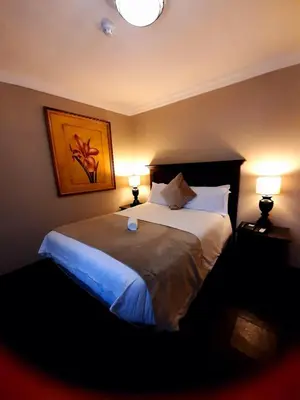 a bedroom with a large bed with two lamps at Eco Park Lodge in Centurion