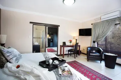 a bedroom with a bed with a table and chairs at Eco Park Lodge in Centurion