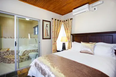 a bedroom with a bed and a bathroom with a tub at Eco Park Lodge in Centurion