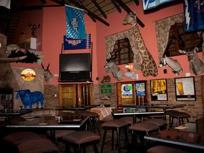 a restaurant with tables and chairs and a wall with animals on it at Golden Pillow Guest House in Polokwane