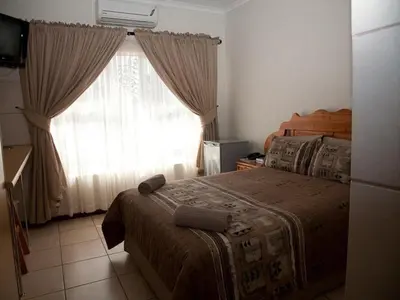 a bedroom with a bed and a window with curtains at Golden Pillow Guest House in Polokwane