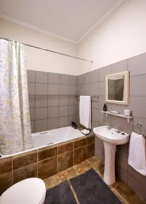 a bathroom with a tub and a sink and a toilet at The BeeKeeper's Inn in Louis Trichardt