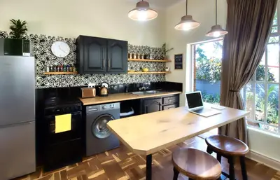 a kitchen with black cabinets and a table with a laptop at The BeeKeeper's Inn in Louis Trichardt
