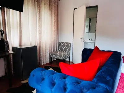 a living room with a blue couch with red pillows at Aloe 40 in Burgersfort