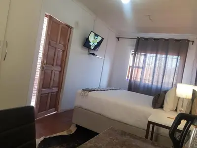 a bedroom with a bed and a window and a television at Aloe 40 in Burgersfort