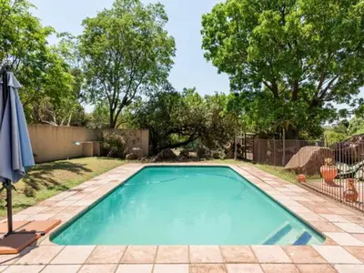 a swimming pool in a yard with a fence and trees at 1 Bedroom Cottage in Midrand