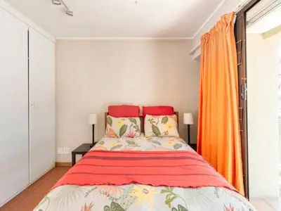 a bedroom with a large bed with orange curtains at 1 Bedroom Cottage in Midrand