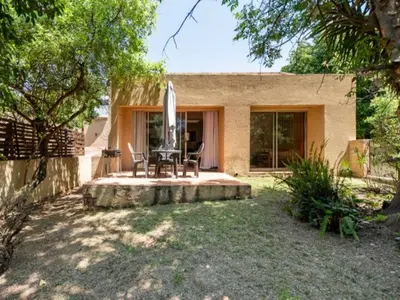 a house with a patio with a table and a surfboard at 1 Bedroom Cottage in Midrand