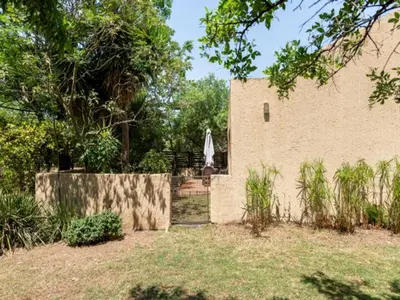 a building with a fence and an umbrella in a yard at 1 Bedroom Cottage in Midrand