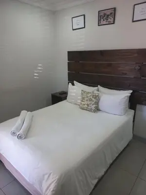 a bedroom with a large bed with white sheets and pillows at Triple9 Hatfield Guesthouse in Pretoria