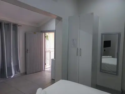 a white room with a bed and a mirror at Triple9 Hatfield Guesthouse in Pretoria
