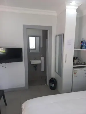 a white bedroom with a sink and a bathroom at Triple9 Hatfield Guesthouse in Pretoria