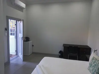 a bedroom with a bed and a table and a desk at Triple9 Hatfield Guesthouse in Pretoria