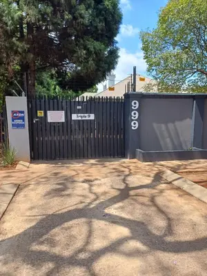 a black fence with a sign on it next to a driveway at Triple9 Hatfield Guesthouse in Pretoria