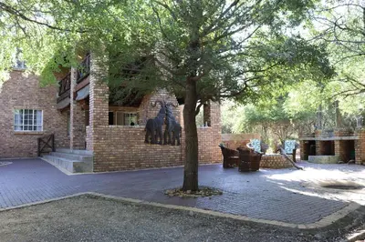 a tree sitting in front of a brick building at Mellivora Lodge in Marloth Park