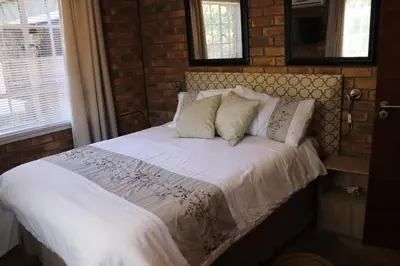 a bed with white sheets and pillows in a bedroom at Mellivora Lodge in Marloth Park