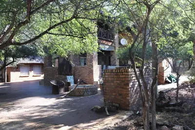 a brick building with a brick wall and trees at Mellivora Lodge in Marloth Park