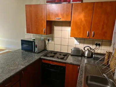 a kitchen with wooden cabinets and a stove and a microwave at Midrand Ninth on Lever Shalom in Midrand