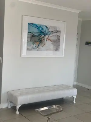 a white bench against a white wall with a painting at The Blyde in Pretoria