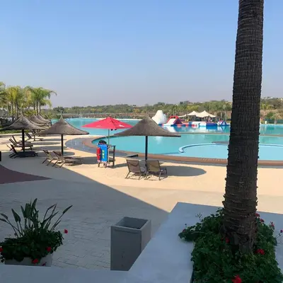 a resort with a pool with umbrellas and chairs at The Blyde in Pretoria