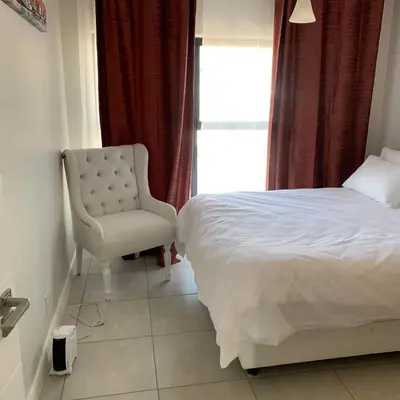 a bedroom with a bed and a chair and a window at The Blyde in Pretoria