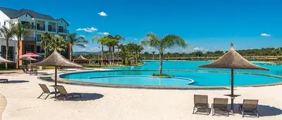a swimming pool with chairs and umbrellas on a beach at The Blyde in Pretoria
