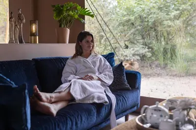 a woman is sitting on a blue couch at Oase by 7 Star Lodges - Greater Kruger Private 530ha Reserve in Hoedspruit