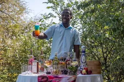 a man holding a drink in front of a table with alcohol at Oase by 7 Star Lodges - Greater Kruger Private 530ha Reserve in Hoedspruit