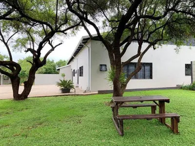 a wooden bench sitting in the grass next to a tree at Stay Harties Accommodation in Hartbeespoort