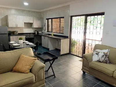 a living room with two couches and a kitchen at Stay Harties Accommodation in Hartbeespoort